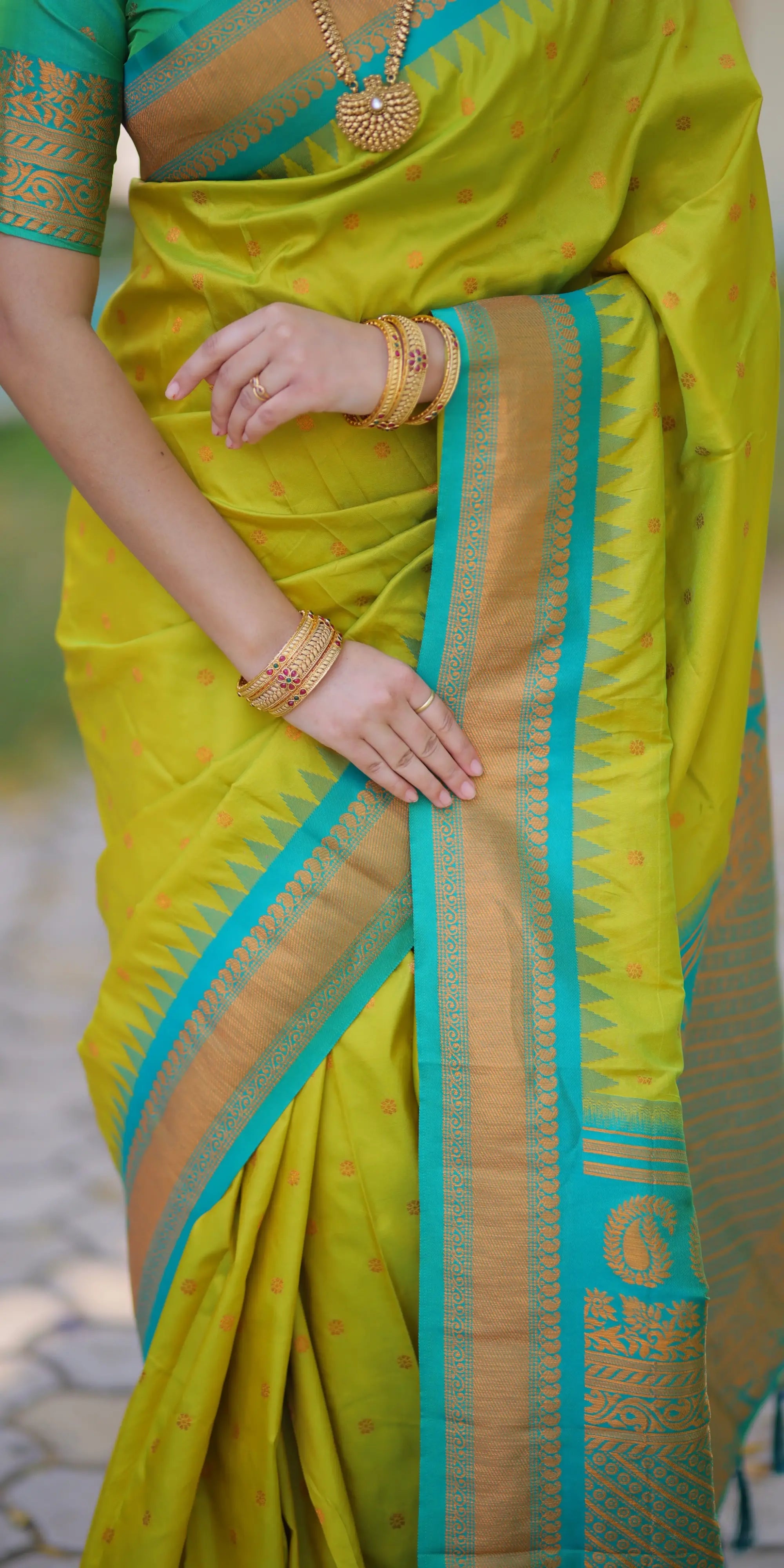Woman wearing a bright yellow saree with green and gold border